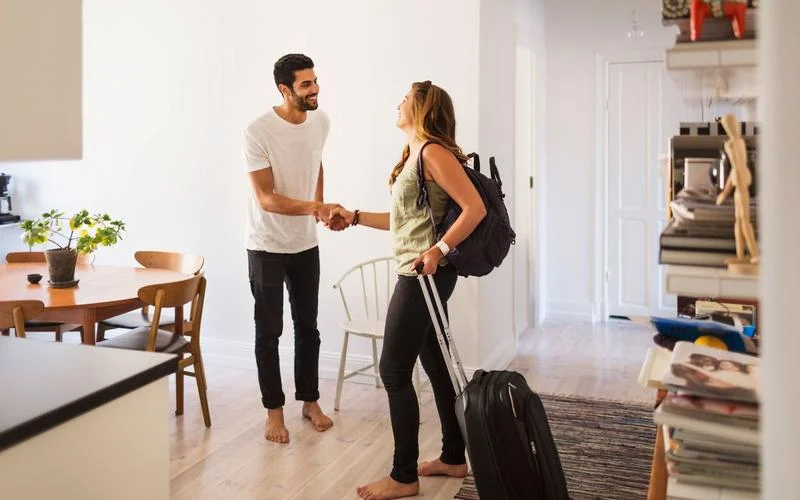 un homme et une femme se sert la main en souriant dans un appartement