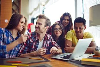 5 personnes sont autour d'une table en souriant 