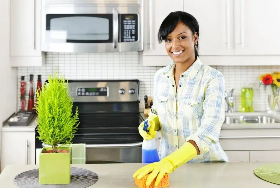 Une femme avec des gants jaune fait le ménage dans une cuisine